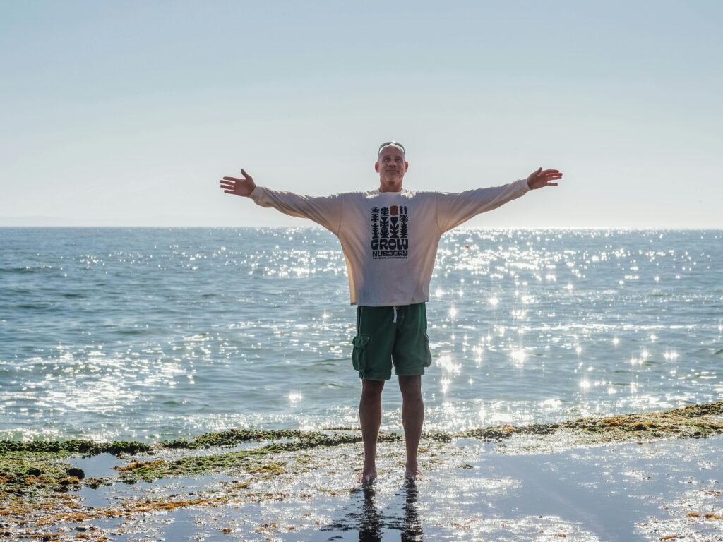 Senior man enjoying the beach with open arms, exuding freedom and joy under the sunny sky.